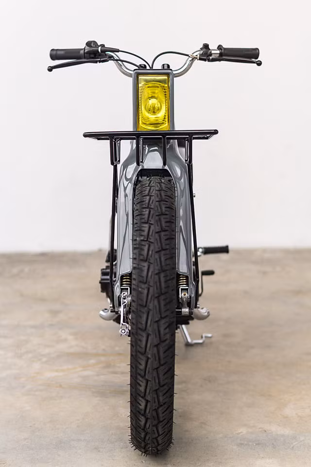 Đèn pha tròn phía trước được đại tu bằng đèn pha hộp màu vàng, tay lái không có vỏ bọc.