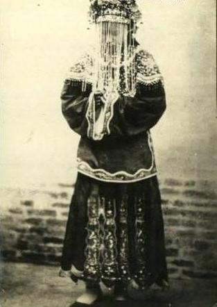 Cô dâu thời nhà Thanh trong trang phục váy cưới truyền thống màu đỏ và đội khăn che mặt.