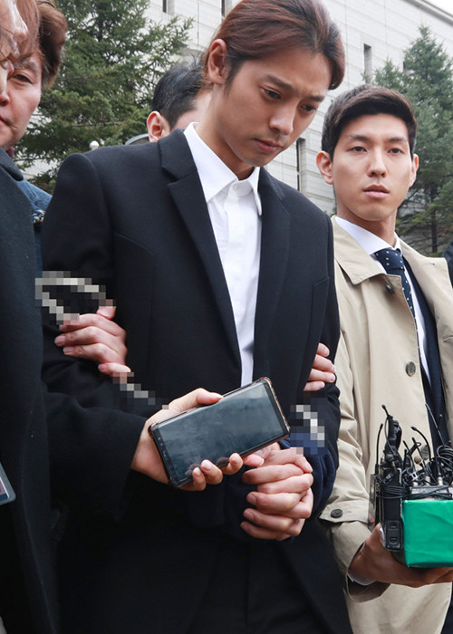 Jung Joon Young liên tục cúi đầu khi bị áp giải đến đồn cảnh sát gần nhất trong khi cảnh sát chờ lệnh bắt giữ chính thức từ tòa án. Ảnh: Chosun