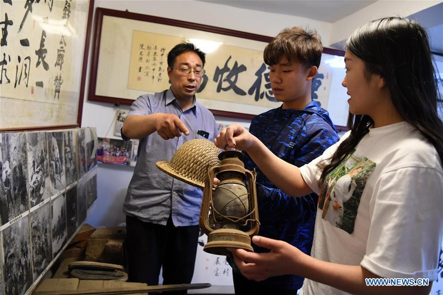 Shen Qingmin (trái), một cư dân trong làng, kể cho mọi người về việc xây dựng đường hầm Guoliang tại nhà của ông ở làng Guoliang ngày 18/5/2017.