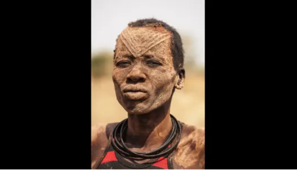 Khuôn mặt của người phụ nữ bộ tộc Mundari phủ đầy tro - một chất khử trùng tự nhiên bảo vệ da khỏi côn trùng.