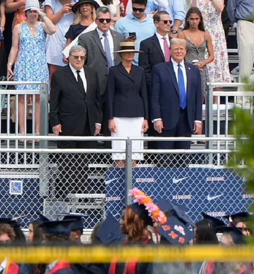 Ông Trump mặc bộ vest tối màu, áo sơ mi trắng và cà vạt xanh ngồi ở hàng ghế đầu tại sự kiện cùng bà Melania và bố vợ.