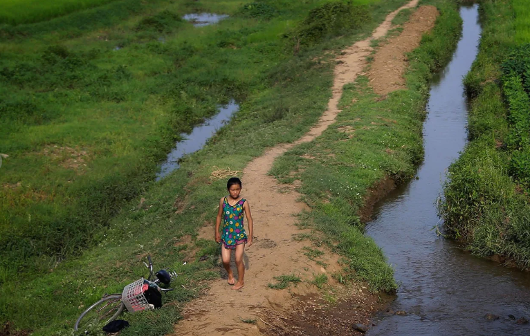 Một bé gái mặc đồ bơi đi bộ gần con suối ở Hamju, Triều Tiên. Bức ảnh chụp ngày 20/7/2017.