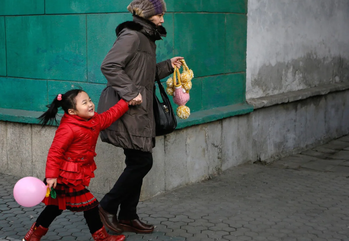 Người phụ nữ dắt con gái đi bộ trên đường phố trung tâm Bình Nhưỡng ngày 18/2/2014.