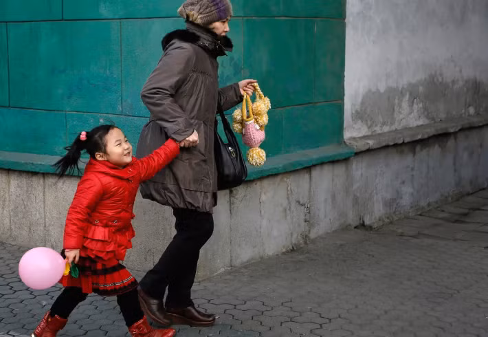 Người phụ nữ dắt con gái đi bộ trên đường phố trung tâm Bình Nhưỡng ngày 18/2/2014.