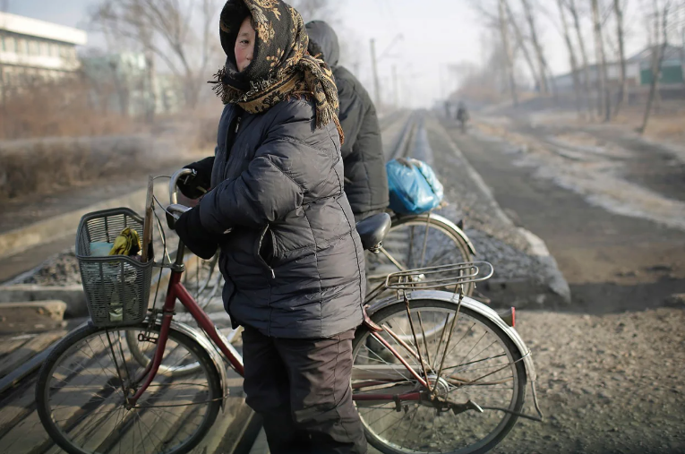 Người phụ nữ dắt xe đạp qua đường ray tàu ở Chollima, Nampo, ngày 7/1/2017.