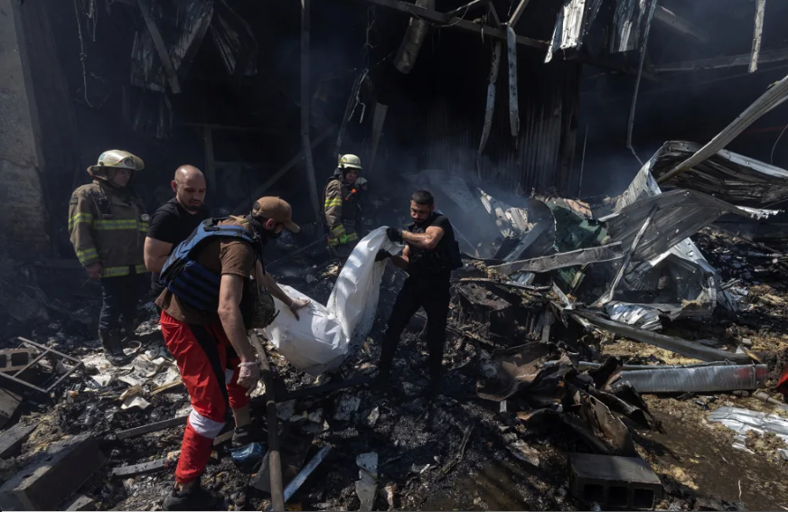 Các tình nguyện viên khiêng thi thể một người thiệt mạng ra khỏi nhà in ở Kharkov.