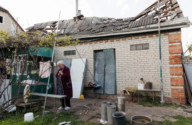 Người phụ nữ đứng gần ngôi nhà bị hư hại của mình ở ngoại ô Kharkov ngày 2/5. Ảnh: Kyiv Independent.