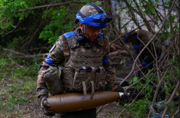 Một thành viên của Lữ đoàn tác chiến số 13 'Khartiia' Ukraine mang quả đạn 152 mm lắp vào lựu pháo D-20 trước khi khai hỏa về phía Quân đội Nga tại tiền tuyến ở Kharkov ngày 21/5.