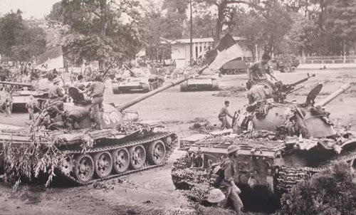 Tại triển lãm, người xem được nhìn lại những bức ảnh nổi tiếng của nghệ sĩ Đinh Quang Thành, trong đó có bức “Quân đoàn 3 truy kích địch trong sân bay Tân Sơn Nhất”. Nghệ sĩ Đinh Quang Thành vẫn bảo rằng, mình là người may mắn khi trực tiếp chứng kiến miền Nam được giải phóng. Nhờ đó mà ông lưu giữ được những khoảnh khắc ý nghĩa. Mặc dù không chụp được bức ảnh treo cờ trên nóc Dinh Thống nhất nhưng ông đã chớp được khoảnh khắc các chiến sĩ Sư đoàn 10, Quân đoàn 3 truy kích địch trong sân bay Tân Sơn Nhất. Đó cũng chính là tác phẩm ghi đậm dấu ấn trong phóng sự ảnh “Giải phóng Sài Gòn” của ông. Ảnh: Xe tăng số hiệu 390 húc đổ cổng Dinh Thống nhất cùng xe tăng 843 tiến vào án ngữ ngay trước thềm Dinh.