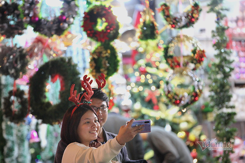 Đôi bạn trẻ tranh thủ checkin trên con phố rực rỡ ánh sáng.