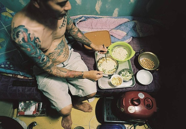 Một người khác đang nấu mỳ và rau ngay trong phòng thuê nhỏ xíu.