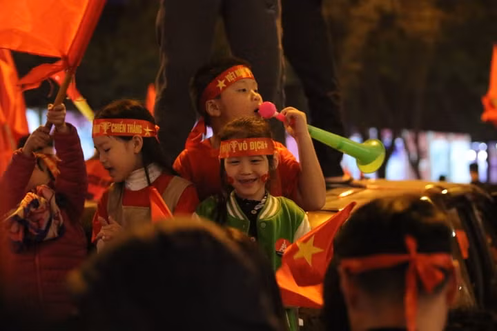 Nhiều cháu bé đã cùng phụ huynh ra đường ho rơ, vẫy cơ, thổi kèn ăn mừng chiến thắng. (Infonet)