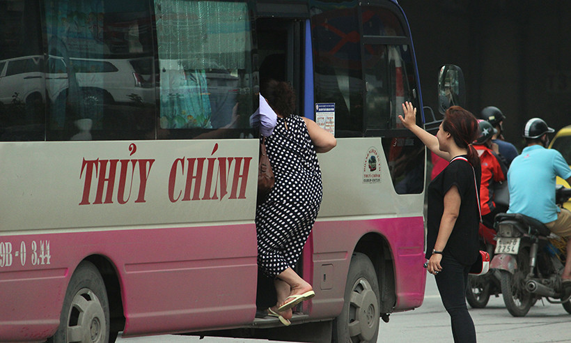 Tại khu vực trước cổng bến xe khách Mỹ Đình (Hà Nội), tình trạng xe khách dừng đón trả khách liên tục diễn ra trong trưa nay. Trong ảnh phụ xe khách BKS: 19B-003.44 nhanh tay mở cửa bắt hai hành khách lên xe.