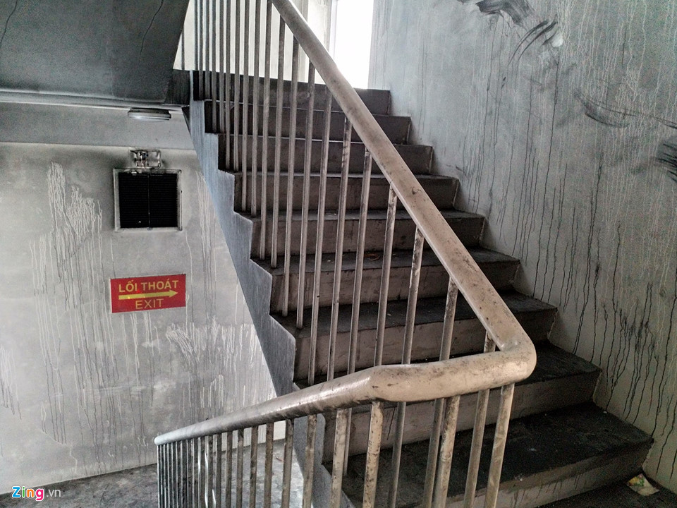 Gần 20 ngày sau vụ cháy tại chung cư Carina Plaza, cầu thang khu nhà block A, nơi thiệt hại nhiều nhất, vẫn đen kịt vì khói. Những mảng tường ám muội than, không khí nặng mùi cháy khét, khói bụi, và rác thải để lâu ngày. Khu nhà này đang được dọn dẹp. Không còn bảo vệ nào ở đây.