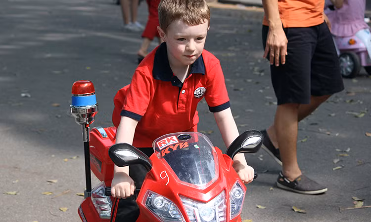 Một em bé nước ngoài thích thú với chiếc mô tô siêu nhỏ trên phố đi bộ Hà Nội.