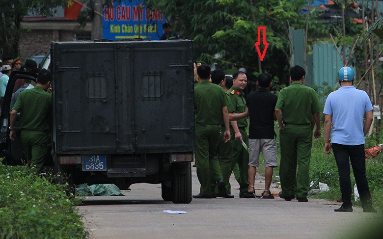 Nghi phạm mặc quần lửng trắng, áo đen bị khóa chân và còng tay được cảnh sát dẫn giải thực nghiệm hiện trường.