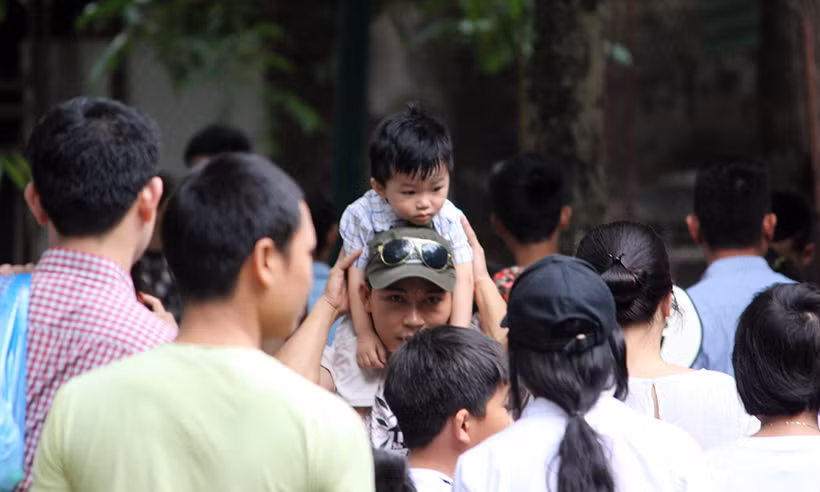Do công viên quá tải nên phụ huynh phải cõng con nhỏ lên vai mới có thể di chuyển được.