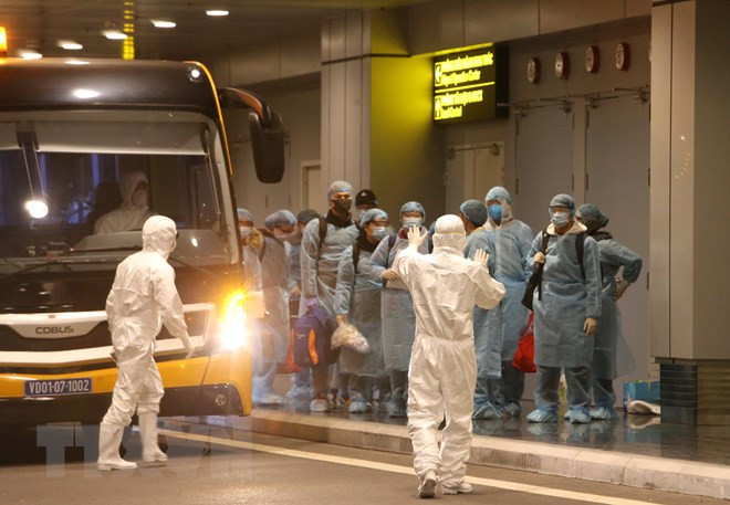 Hiện trường lực lượng chức năng hướng dẫn các công dân kiểm tra y tế và làm thủ tục nhập cản. (Ảnh: TTXVN)