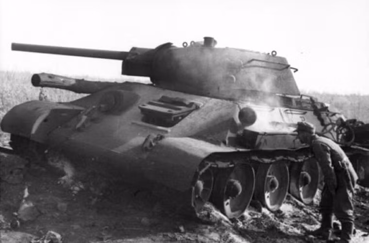 Binh lính Đức đang xem xét một chiếc tăng T-34-76 của Hồng quân Liên Xô bị phá hủy.