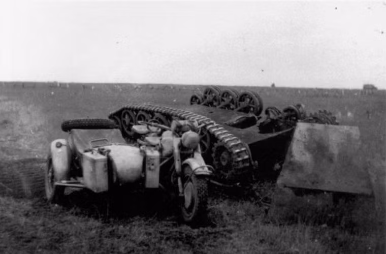 Xe mang bom cảm tử điều khiển từ xa B-IV nằm lật ngửa bụng bên cạnh chiếc xe máy BMW R-75.