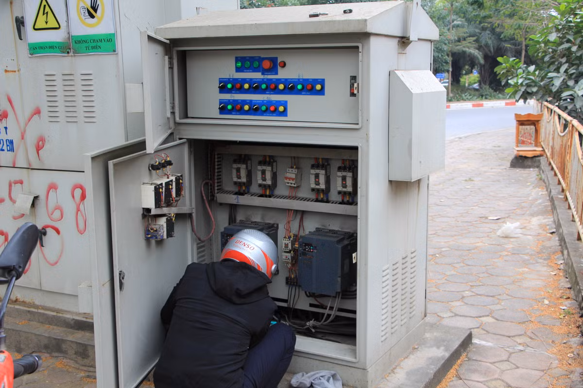 Nhóm công nhân cũng tranh thủ kiểm tra hệ thống điện của trạm bơm trước khi tìm đến một đống lửa để sưởi ấm sau nhiều tiếng móc rác dưới dòng sông Tô Lịch