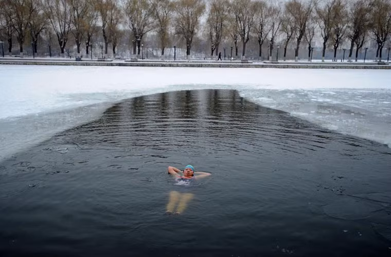 Một người bơi đang thả lỏng cơ thể ngắm cảnh trời đông tuyết phủ trắng xóa.