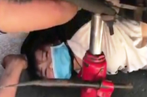 Nữ nạn nhân bị mắc kẹt dưới gầm xe, nhiều người phải tìm đủ cách để nâng xe khách đưa nạn nhân ra ngoài.