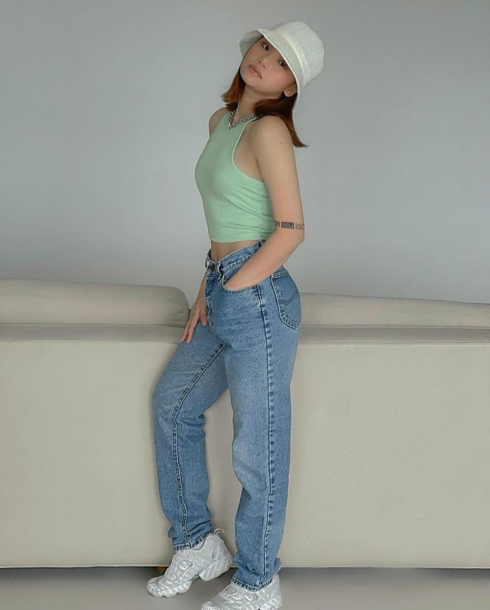 Miu Lê có cách chọn trang phục tương tự với áo tank top màu xanh mát mắt, mix thêm mũ bucket thời trang.