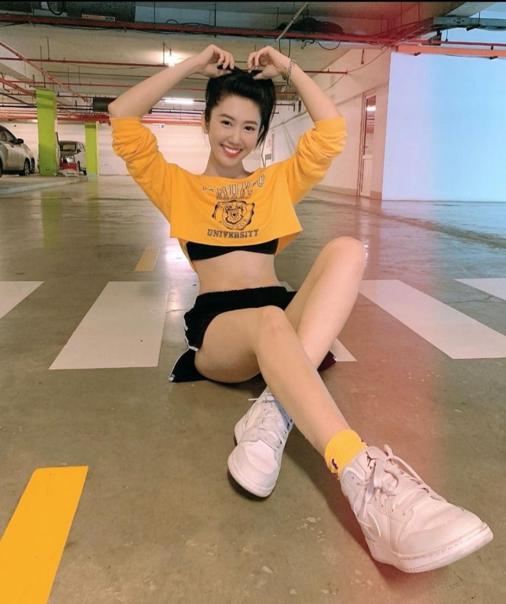 Thúy Ngân trẻ trung, năng động với set đồ tập màu đen: Áo crop-top tay dài màu vàng nổi bật, đi giày sneaker và tất cùng màu với áo.