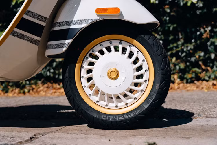 Mẫu scooter cao cấp được trang bị bộ mâm đa chấu 12 inch được sơn cùng màu với thân xe, kết hợp với viền vàng và khóa trung tâm bắt mắt.