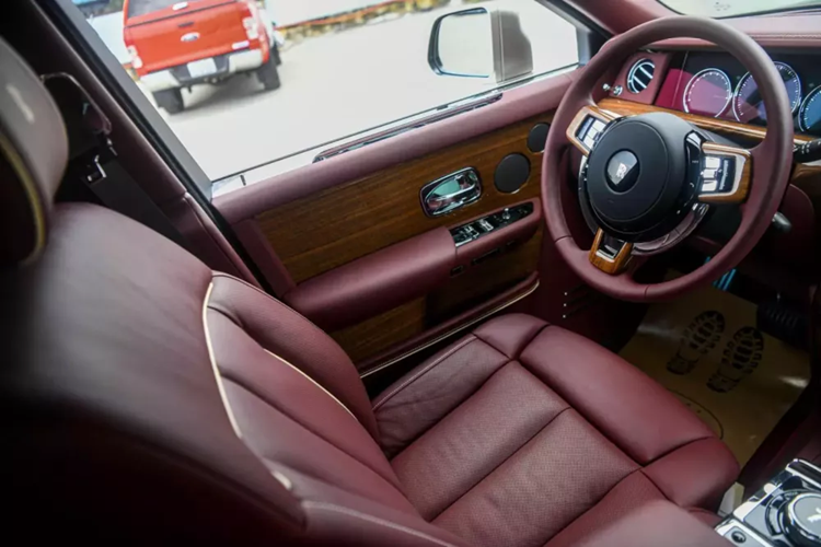 Tiến vào bên trong khoang lái, chiếc xe siêu sang Rolls-Royce Phantom thế hệ thứ 8 này được phủ màu sắc là đỏ mận, cùng với nhiều chi tiết ốp gỗ quý hiếm. Đáng chú ý, xe có trang bị tùy chọn vách ngăn cho hàng ghế trước và sau, loại này dạng kính, có rèm che.