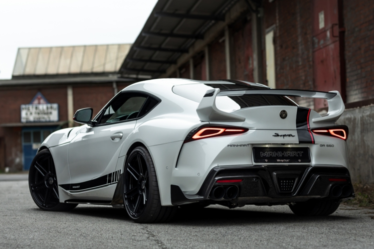 Phần cánh gió cỡ lớn của mẫu Toyota GR Supra độ Manhart gây ấn tượng với thiết kế hài hòa, ăn nhập tổng thể. Xe cũng đồng thời được nâng cấp thêm cánh gió trước và ốp sườn tích hợp cánh gió. Manhart cũng cung cấp ốp gương và ốp đèn hậu bằng sợi carbon, cùng với bộ decal màu đen và đỏ tùy chọn.