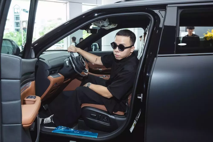 Phong cách đi nhận xe VinFast VF9 của Hoàng Touliver cũng rất ngầu, anh diện đồ đen, đi giày đen và không quên đeo cặp kính màu đen. Điểm sáng trong trang phục này phải kể đến đế giày màu trắng và đồng hồ đắt tiền màu sáng.