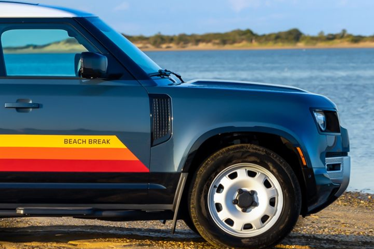 Phần ngang hông mẫu xe SUV Land Rover Defender Beach Break thu hút sự chú ý với bộ họa tiết năm sọc màu ombre chuyển từ đỏ sang vàng, lấy cảm hứng từ sắc màu của hoàng hôn trên bãi biển. Bên cạnh đó, xe còn được bổ sung một số trang bị off-road như giá nóc, bậc lên xuống và hộp phụ kiện gắn bên hông.