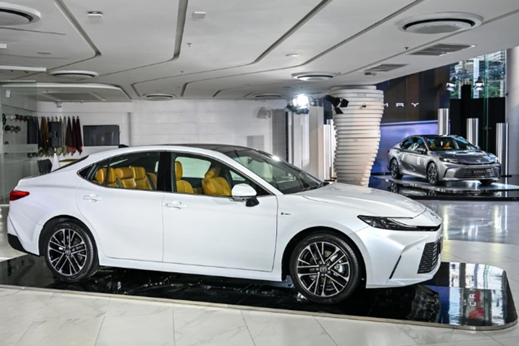 Khu vực đầu xe gây ấn tượng với cụm đèn pha hình cá mập đầu búa, lấy cảm hứng từ “người anh em” Prius. Ở phiên bản cao cấp nhất HEV Premium Luxury, khách hàng mua xe sedan Toyota Camry 2025 sẽ có đặc quyền với kiểu phối màu xe ngoại thất trắng và nội thất màu nâu vàng da bò.