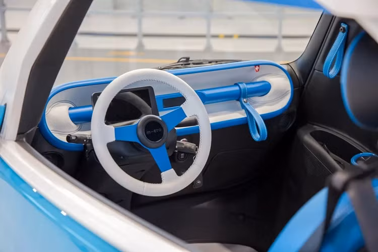 Khoang lái rất cơ bản của Microlino Spiaggina với vô lăng 3 chấu, cụm đồng hồ kỹ thuật số và sàn giả gỗ. Nội thất của mẫu ôtô điện mini được bọc da thuần chay.