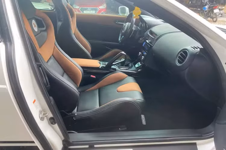 Ngoại thất chiếc xe Mazda RX-8 này mang màu trắng, với cản trước, nẹp sườn và cản sau sơn màu đen khá liền lạc, xe còn đi kèm bộ mâm độ 5 cánh đơn, khá hợp với 2 vòm bánh xe loe ra đẹp mắt. Nội thất xe được bọc da màu đen -nâu.