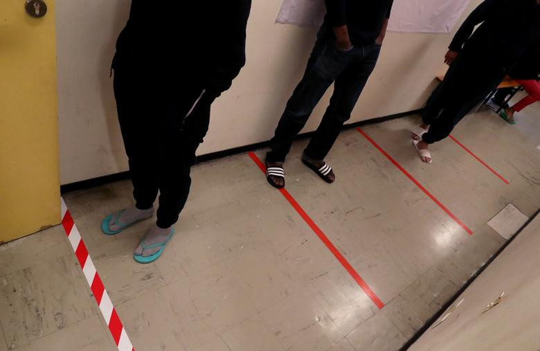 Người vô gia cư tuân thủ khoảng cách xã hội an toàn khi đứng xếp hàng tại trung tâm Hội chữ thập đỏ ở Brussels, Bỉ, ngày 25/3.