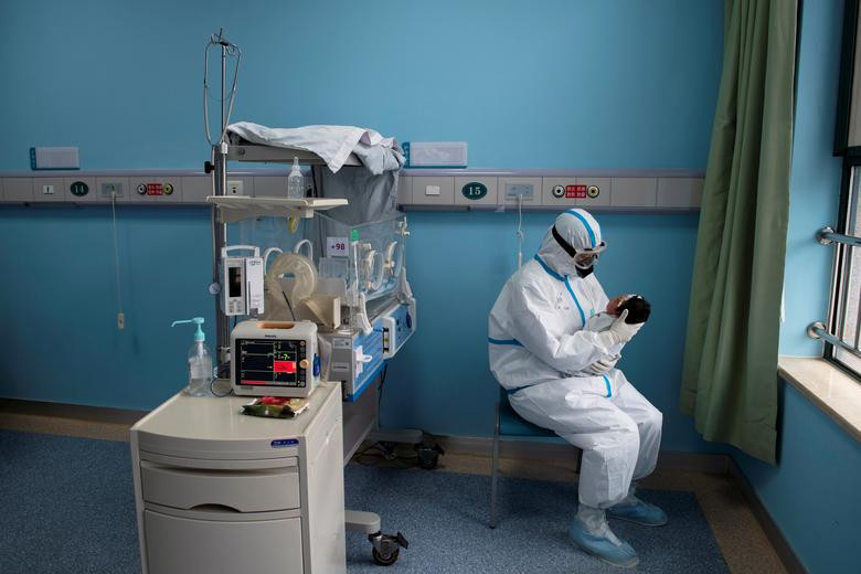 Một y tá mặc đồ bảo hộ chăm sóc em bé sơ sinh mắc Covid-19 tại một khu cách ly ở Bệnh viện Vũ Hán, Trung Quốc, ngày 16/3.