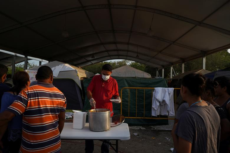 Một tình nguyện viên đeo khẩu trang khi phục vụ đồ ăn cho người dân nhập cư hôm 22/3.