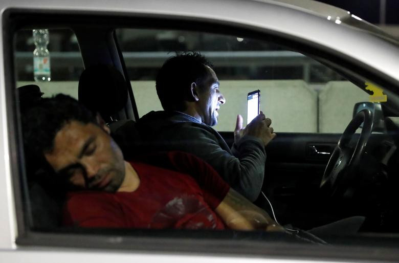Người đàn ông xem điện thoại trên xe ở Hegyeshalom, Hungary, trong lúc chờ đợi để được mở một lối đi đặc biệt qua biên giới Hungary-Áo.