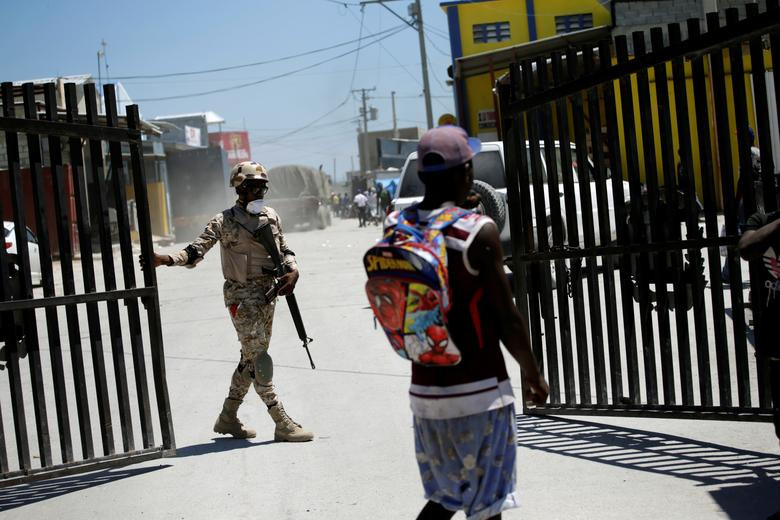 Một thành viên của Lực lượng Vũ trang Cộng hòa Dominica đóng cổng ở biên giới giữa Malpasse, Haiti, và Jimani, Cộng hòa Dominica, ngày 17/3. Được biết, Haiti đã ngừng các chuyến bay từ Châu Âu, Mỹ Latinh và Canada, đồng thời đưa ra lệnh hạn chế đi lại ở biên giới với nước láng giềng Cộng hòa Dominica để ngăn dịch bệnh lây lan.