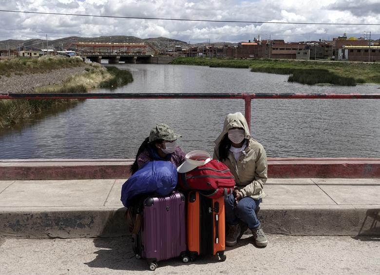 Hai người phụ nữ ngồi trên cầu quốc tế giữa Peru và Bolivia ở Desaguadero, Bolivia, ngày 17/3. Họ bị "mắc kẹt" khi chính phủ Peru thông báo đóng cửa biên giới trước tình hình dịch bệnh diễn biến phức tạp.