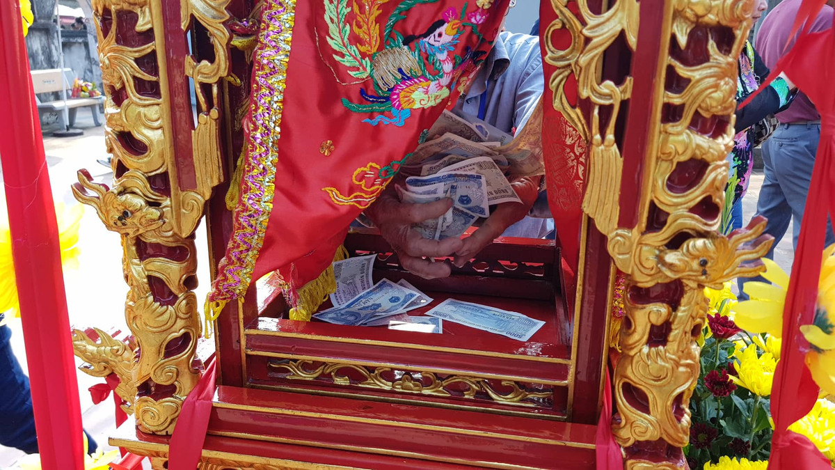 Một người đàn ông của Ban tổ chức thi thoảng ra bốc tiền lẻ trong kiệu ấn.