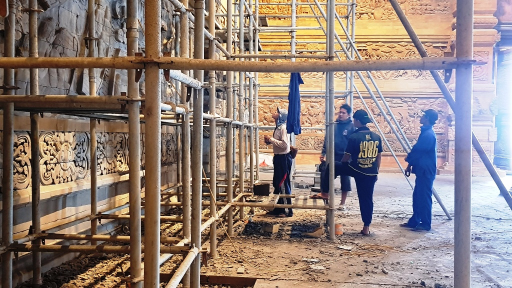 Các nghệ nhân đang hoàn thiện nốt bức tranh bằng đá núi lửa trên tường điện Quan Âm.