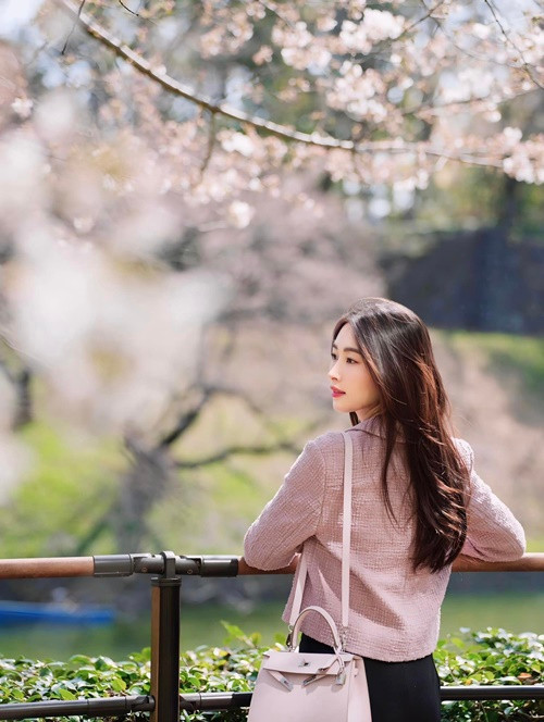 Bà mẹ hai con diện áo khoác gam hồng pastel và sử dụng túi xách cùng tông màu.