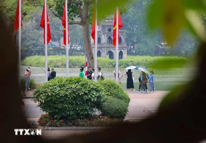 Khách du lịch quốc tế vẫn lựa chọn phố đi bộ Hồ Gươm để tham quan, ngắm cảnh dù thời tiết khắc nghiệt. (Ảnh: Thanh Tùng/TTXVN)