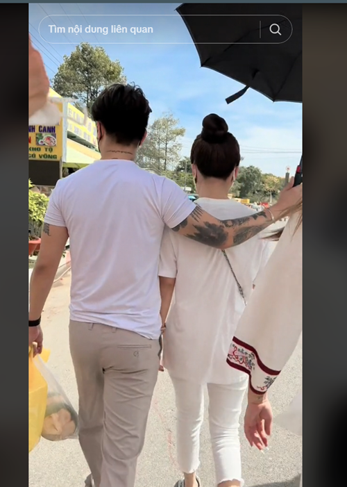 Nam ca sĩ một tay che ô cho vợ một tay xách đồ.