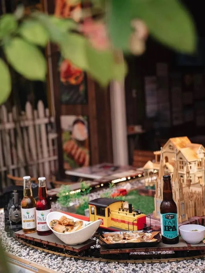 Món ăn sẽ được đặt lên toa chở hàng của mô hình tàu lửa và đưa đến tận bàn khách bằng điều khiển từ xa. Trung bình, tàu sẽ dừng khoảng 15-20 giây ở mỗi bàn để khách lấy đồ ăn. Thực đơn được chọn lọc với 21 món, chủ yếu mang hương vị đặc trưng của các quốc gia trên thế giới như bữa sáng kiểu Anh, xúc xích Đức, spaghetti (Italy), bánh ngô Mexico, bánh trứng Pháp... Một số món Á gồm Tteokbokki (Hàn Quốc), dimsum (Trung Quốc), bún mọc, xôi chiên hay bún chả giò (Việt Nam). Mức giá dao động 29.000-179.000 đồng/món. Ảnh: Tàu Lửa Quán - The Train Restaurant.